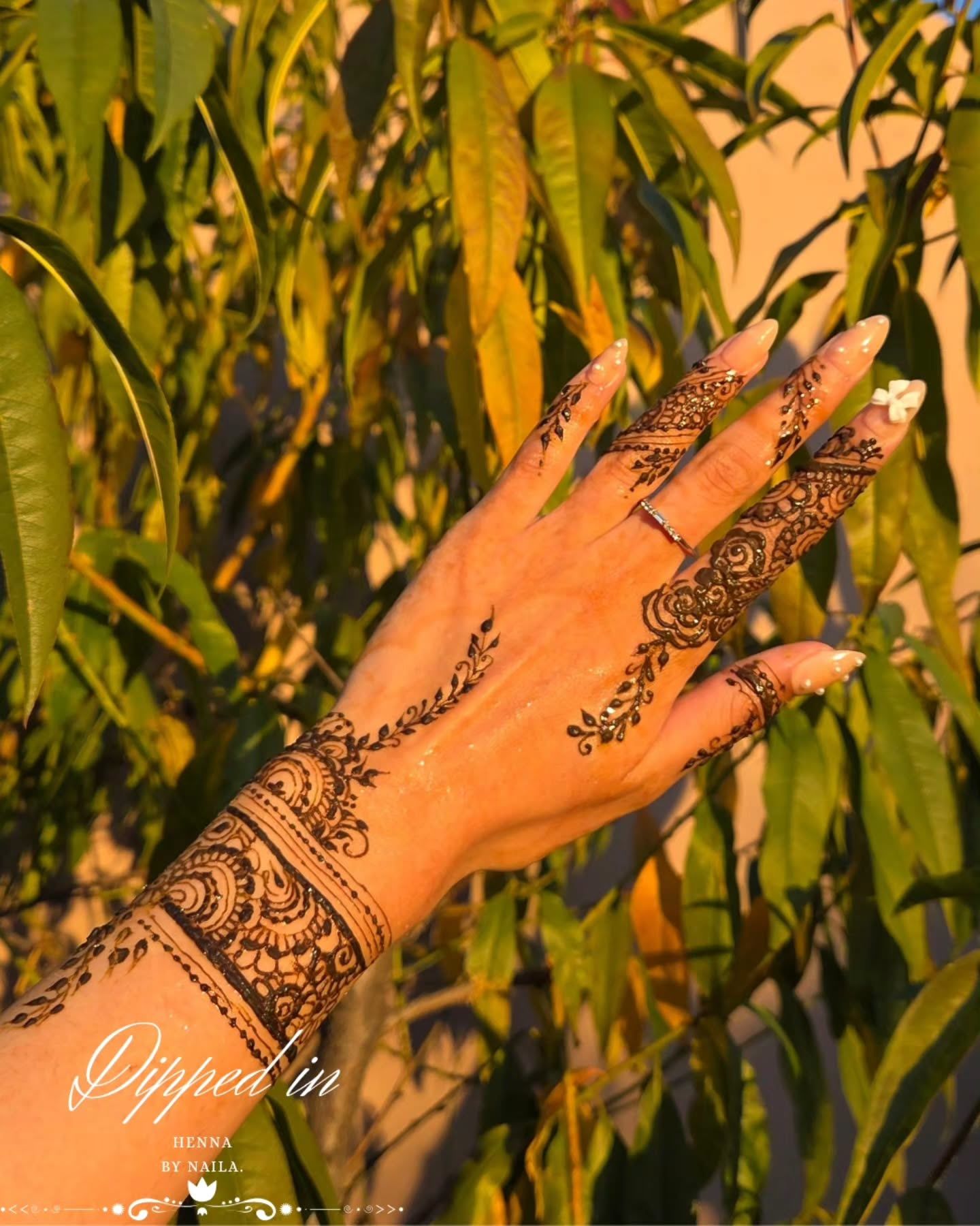 Fine-line henna on the fingers and wrist in golden evening light
