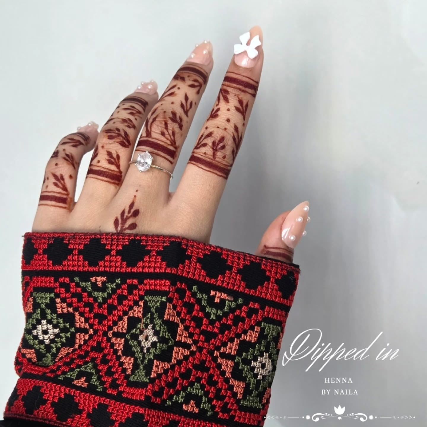 Finger henna above a red and green embroidered sleeve