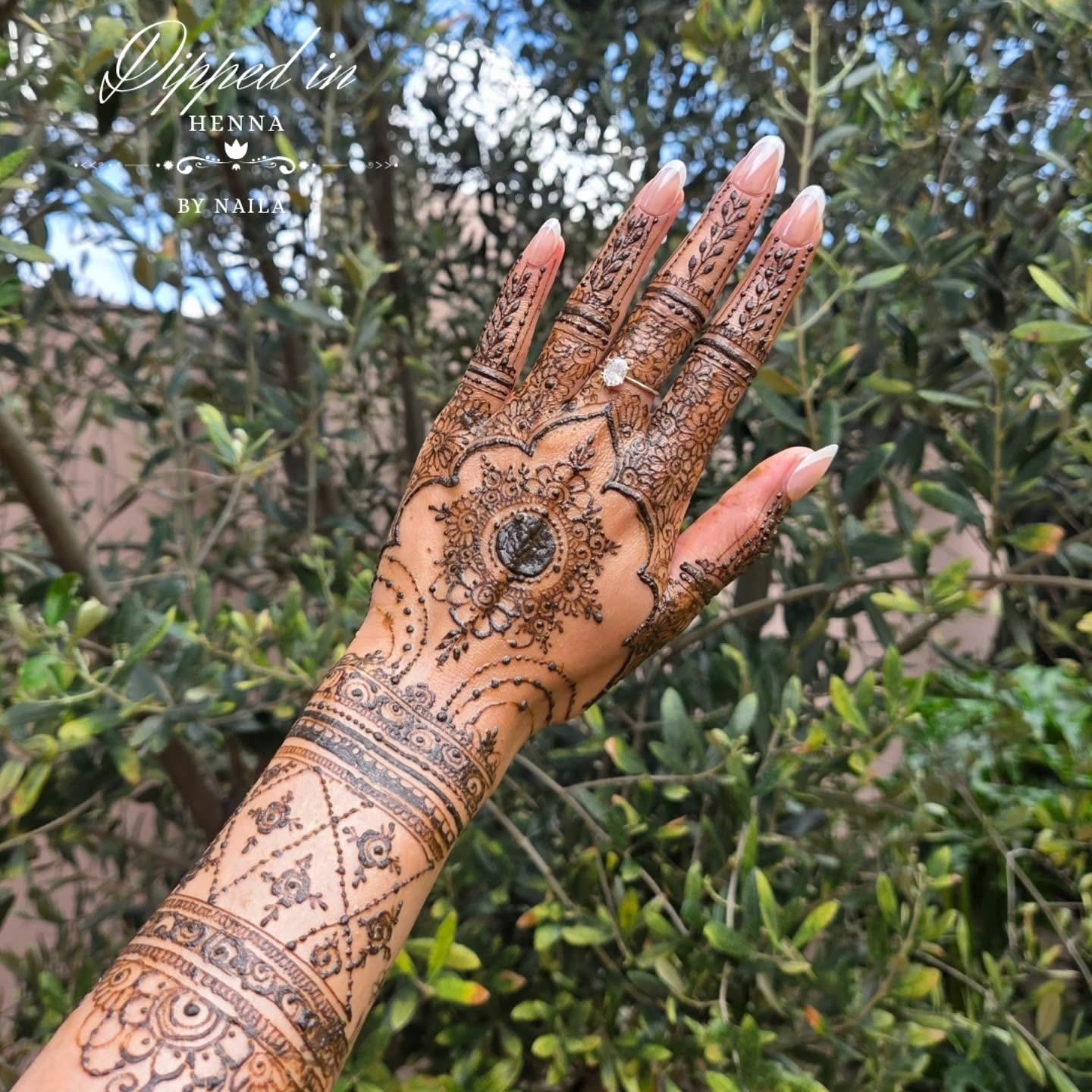 Full arm of fine henna bands against greenery