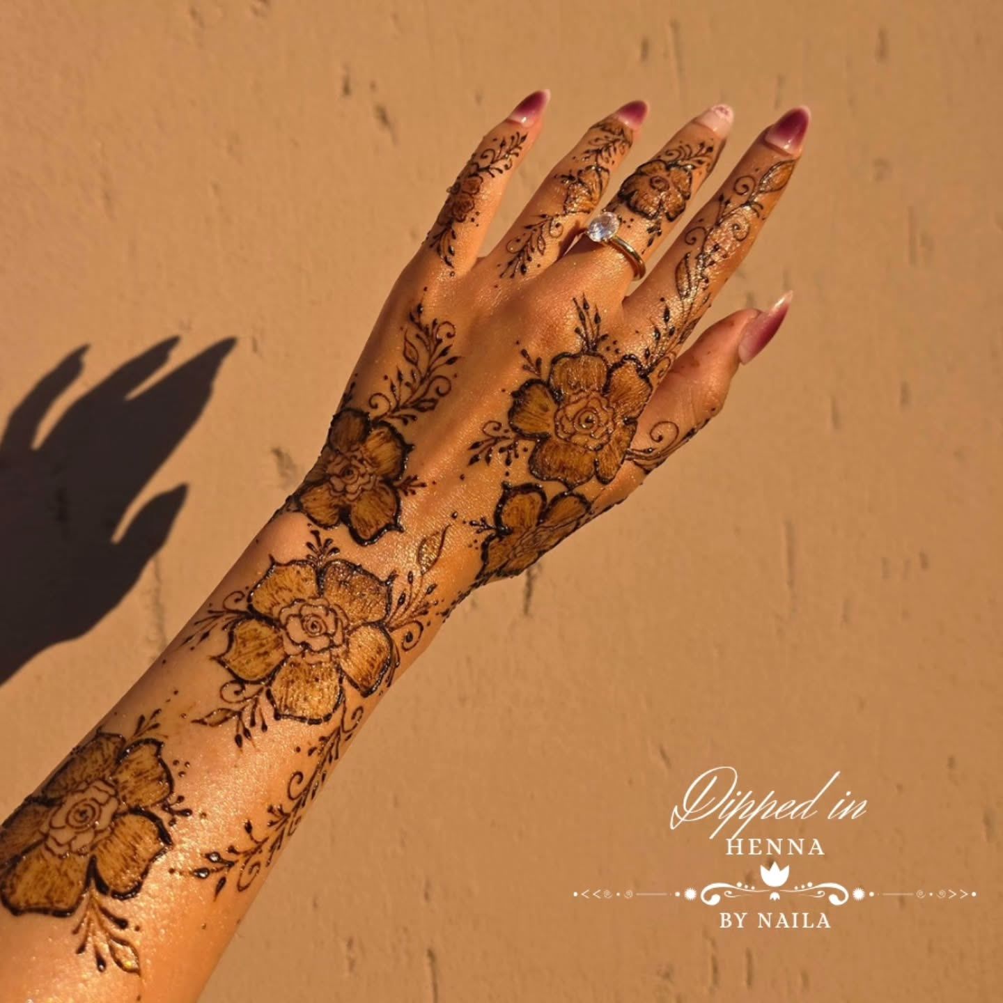 Flowing floral henna on the hand and forearm in warm light